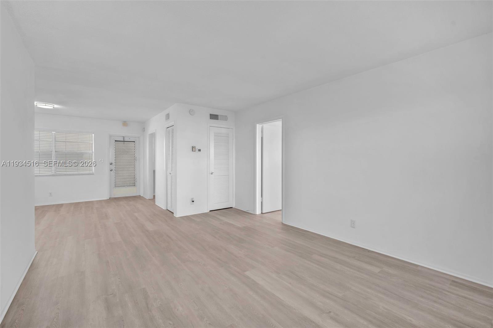 An empty room features light wood-look flooring, white walls, and several interior doors — 1280 NW 43rd Ave # 302, Lauderhill FL 33313, LAUDERHILL, FL