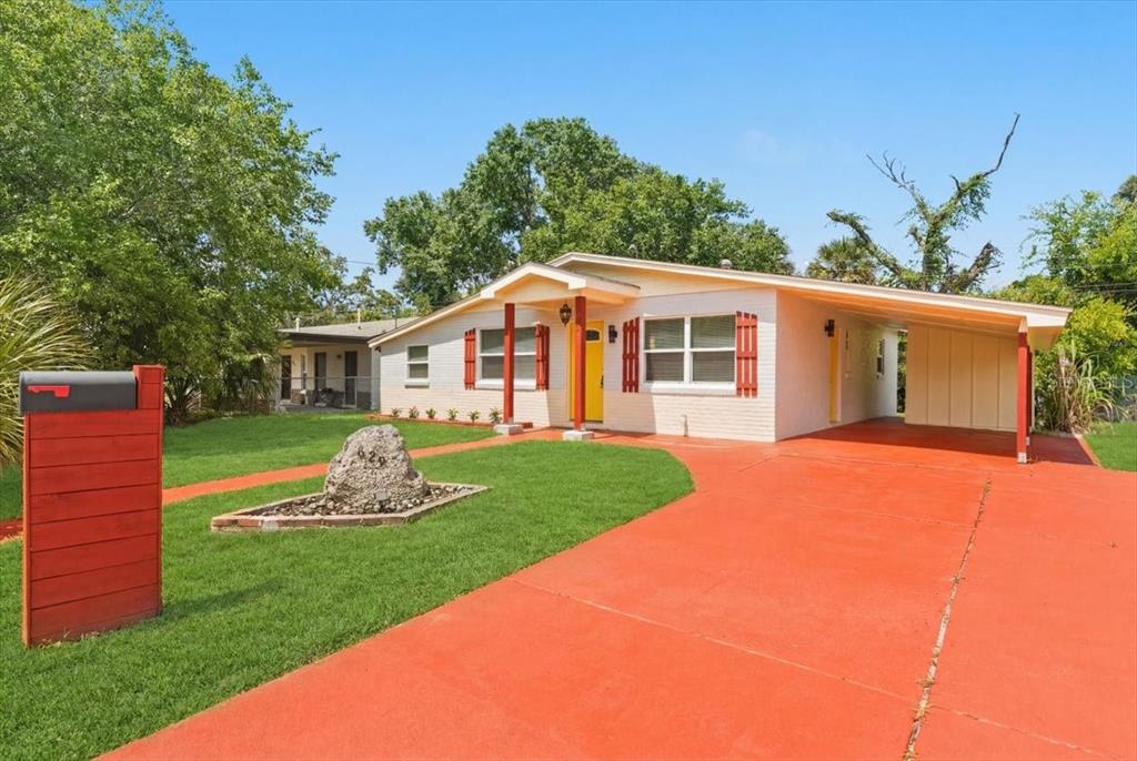 A single-story house with a white brick exterior, red shutters, and a red concrete driveway — 629 CEDAR PARK DRIVE, DAYTONA BEACH, FL