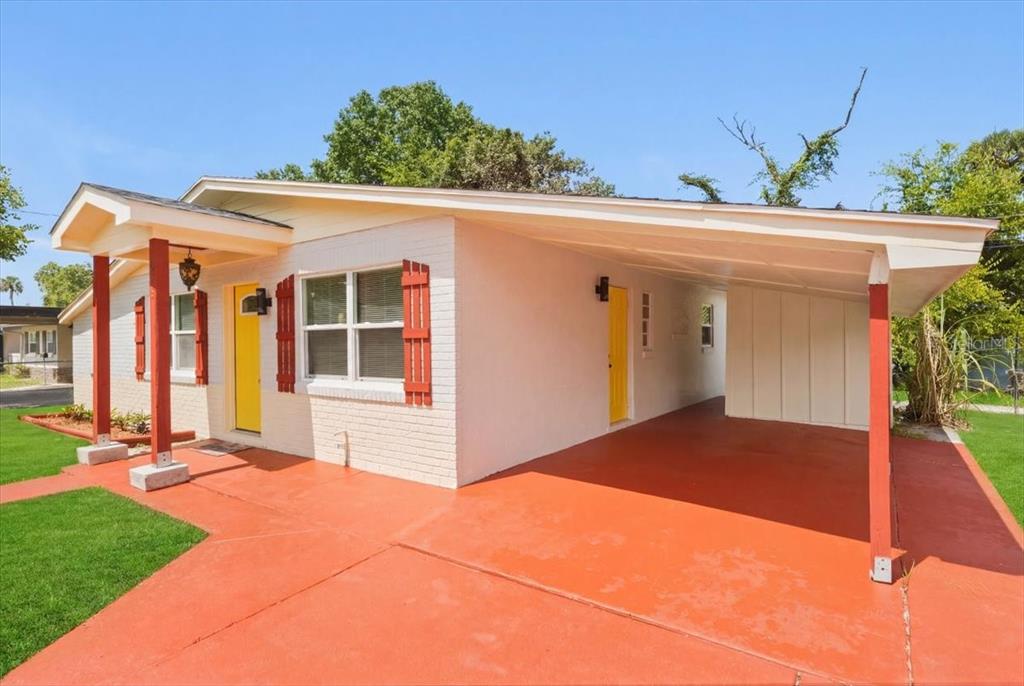 A single-story house with a painted brick exterior, red shutters, and an attached carport — 629 CEDAR PARK DRIVE, DAYTONA BEACH, FL