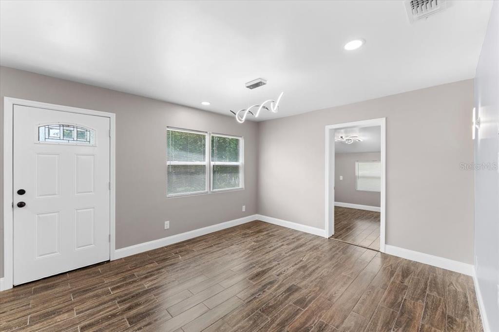 A room with light gray walls, wood-look tile flooring, a white door, and a chandelier — 629 CEDAR PARK DRIVE, DAYTONA BEACH, FL