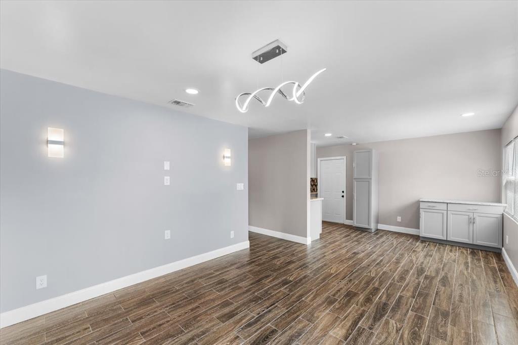 A dining area features light gray walls, wood-look tile flooring, and a modern pendant light — 629 CEDAR PARK DRIVE, DAYTONA BEACH, FL