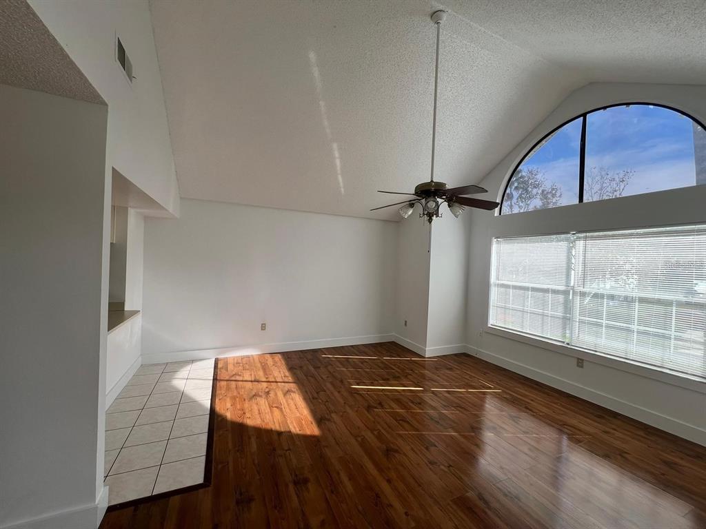 A living room with vaulted ceilings, wood-look flooring, a ceiling fan, and a large window — 3127 FOX SQUIRREL DRIVE UNIT 3127, KISSIMMEE, FL