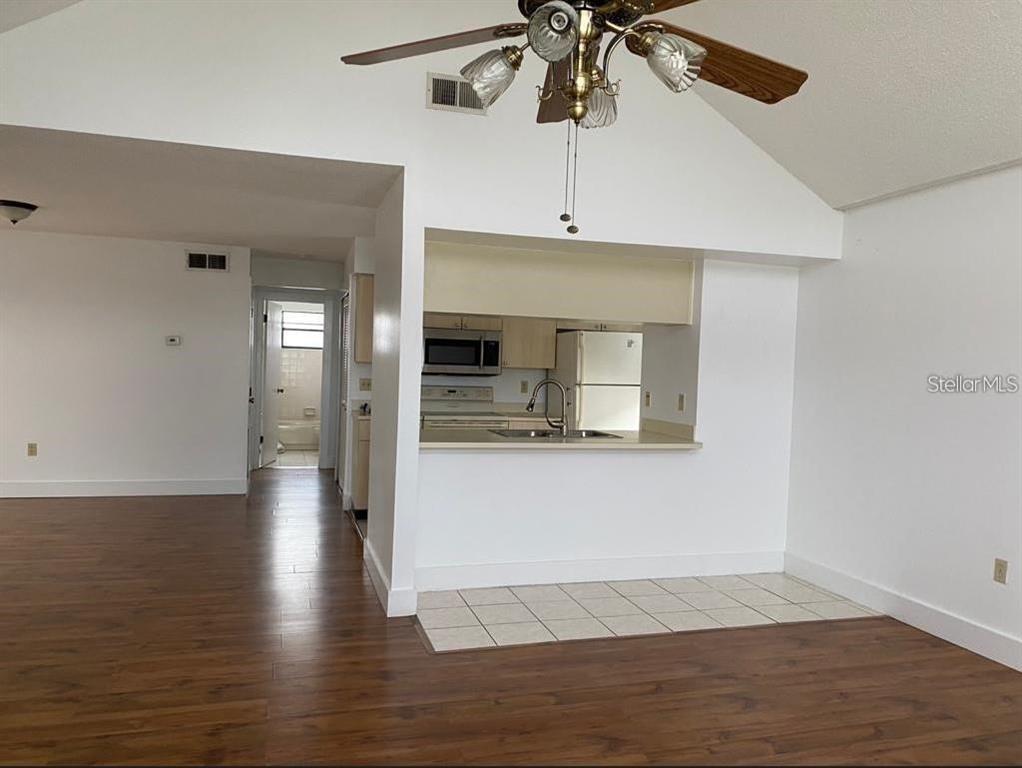 A living room with wood-look flooring opens to a kitchen featuring a breakfast bar — 3127 FOX SQUIRREL DRIVE UNIT 3127, KISSIMMEE, FL