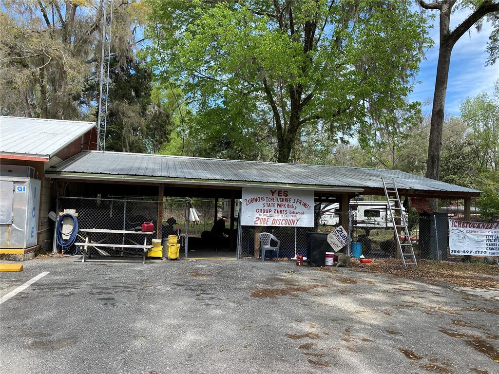 A covered outdoor area with a metal roof, picnic table, and signage for tubing services — 8587 SW ELIM CHURCH ROAD, FORT WHITE, FL
