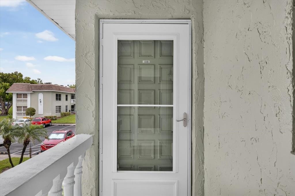 A white storm door with a glass panel is mounted on a textured exterior wall — 1250 S PINELLAS AVENUE UNIT 1008, TARPON SPRINGS, FL