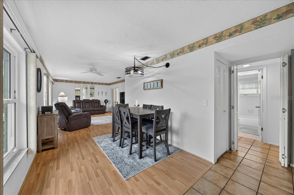 An open-concept dining and living area features wood flooring, a dark dining set, and tile — 1250 S PINELLAS AVENUE UNIT 1008, TARPON SPRINGS, FL