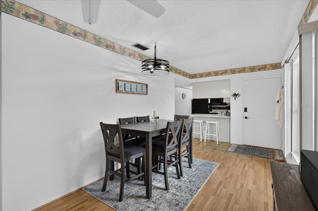 A dining area with a dark wood table, chairs, and a patterned rug on wood flooring — 1250 S PINELLAS AVENUE UNIT 1008, TARPON SPRINGS, FL