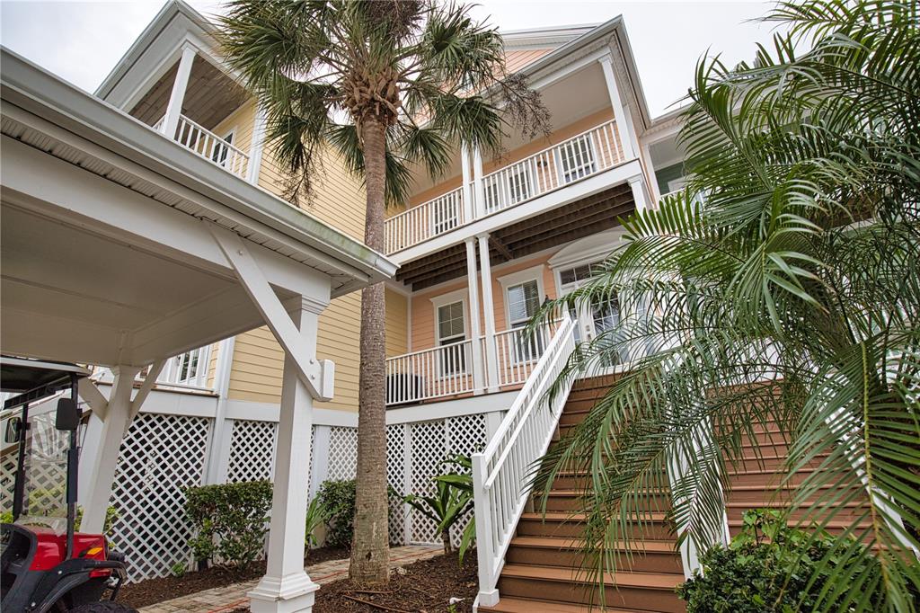 A multi-story house with yellow siding, white railings, and a staircase leading to the entrance — 11723 ANGLERS CLUB DRIVE UNIT 131, PLACIDA, FL