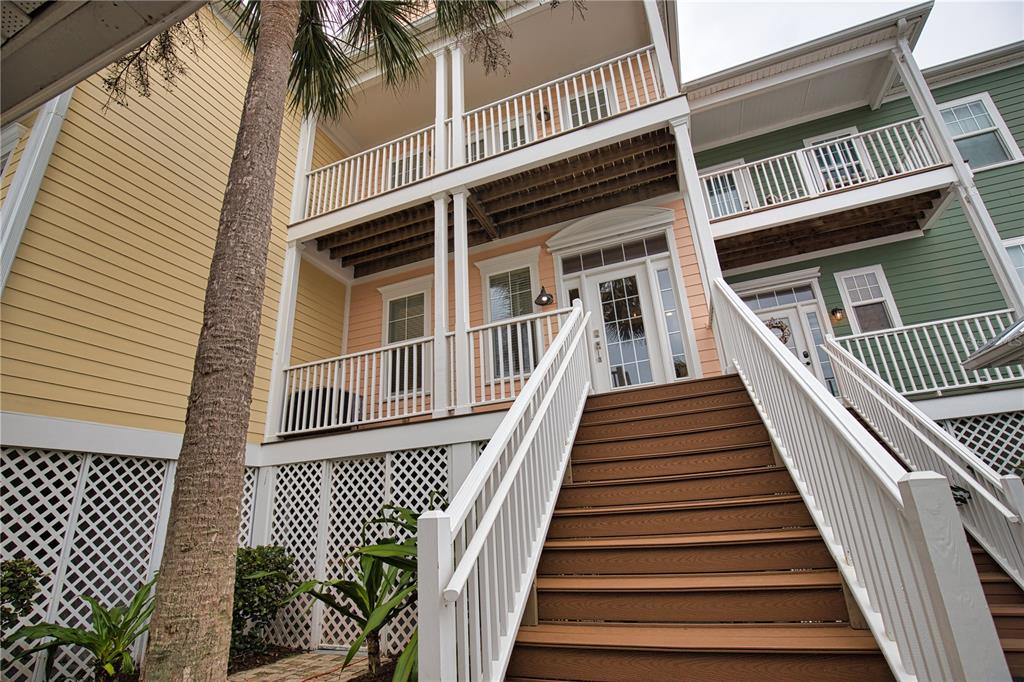 A wooden staircase leads up to the elevated front entrance of a multi-story coastal home — 11723 ANGLERS CLUB DRIVE UNIT 131, PLACIDA, FL