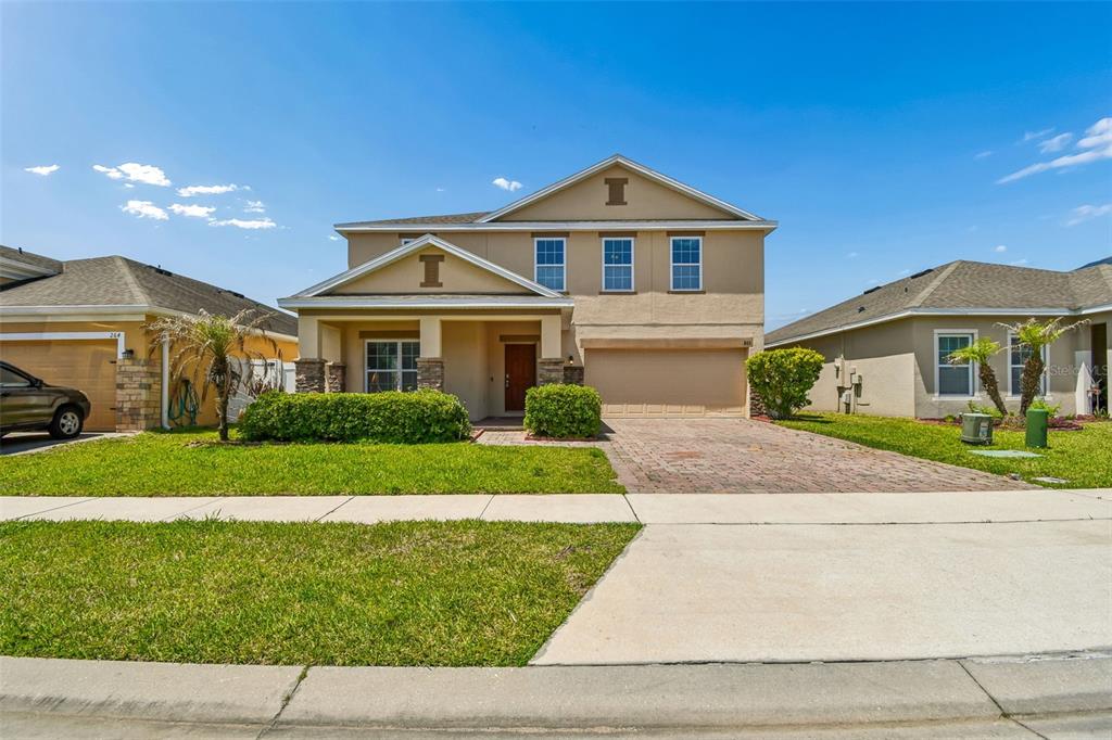 A two-story suburban house with a tan stucco exterior, a front porch, and a driveway — 260 WILLIAMSON DRIVE, DAVENPORT, FL