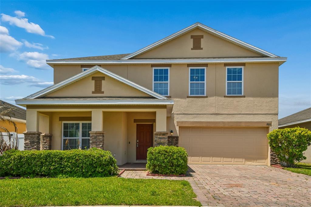A two-story suburban house with a tan stucco exterior, a front porch, and a garage — 260 WILLIAMSON DRIVE, DAVENPORT, FL