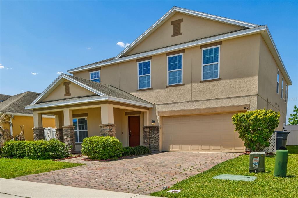 A two-story house with a tan stucco exterior, stone pillars, and a paved driveway — 260 WILLIAMSON DRIVE, DAVENPORT, FL