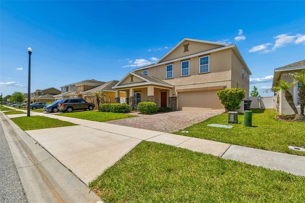 A two-story suburban house with a tan stucco exterior, a brick driveway, and a garage — 260 WILLIAMSON DRIVE, DAVENPORT, FL