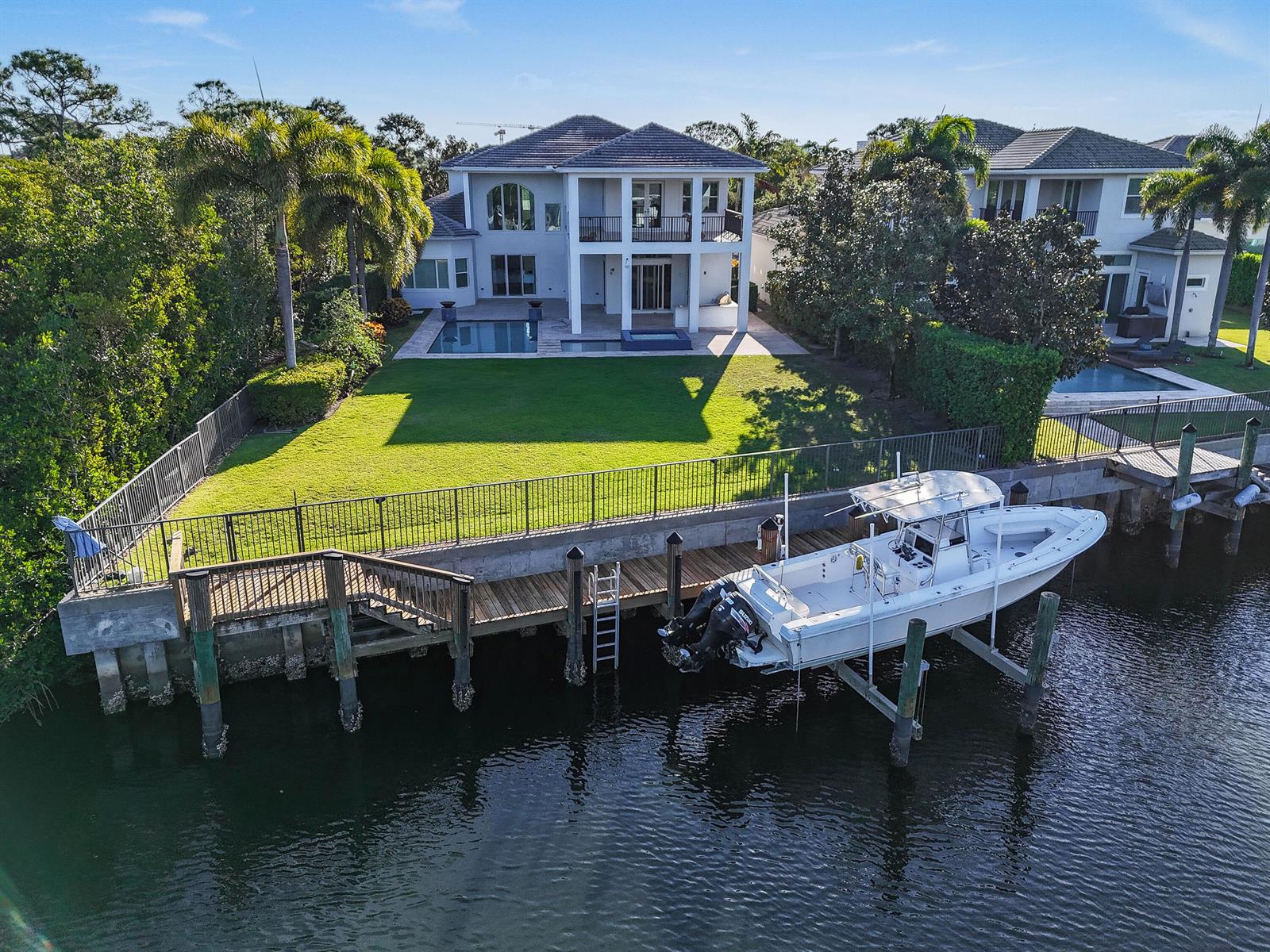 An aerial view shows a two-story house with a pool, lawn, and boat on a lift — 13965 Willow Cay Drive, Juno Beach FL 33408, JUNO BEACH, FL