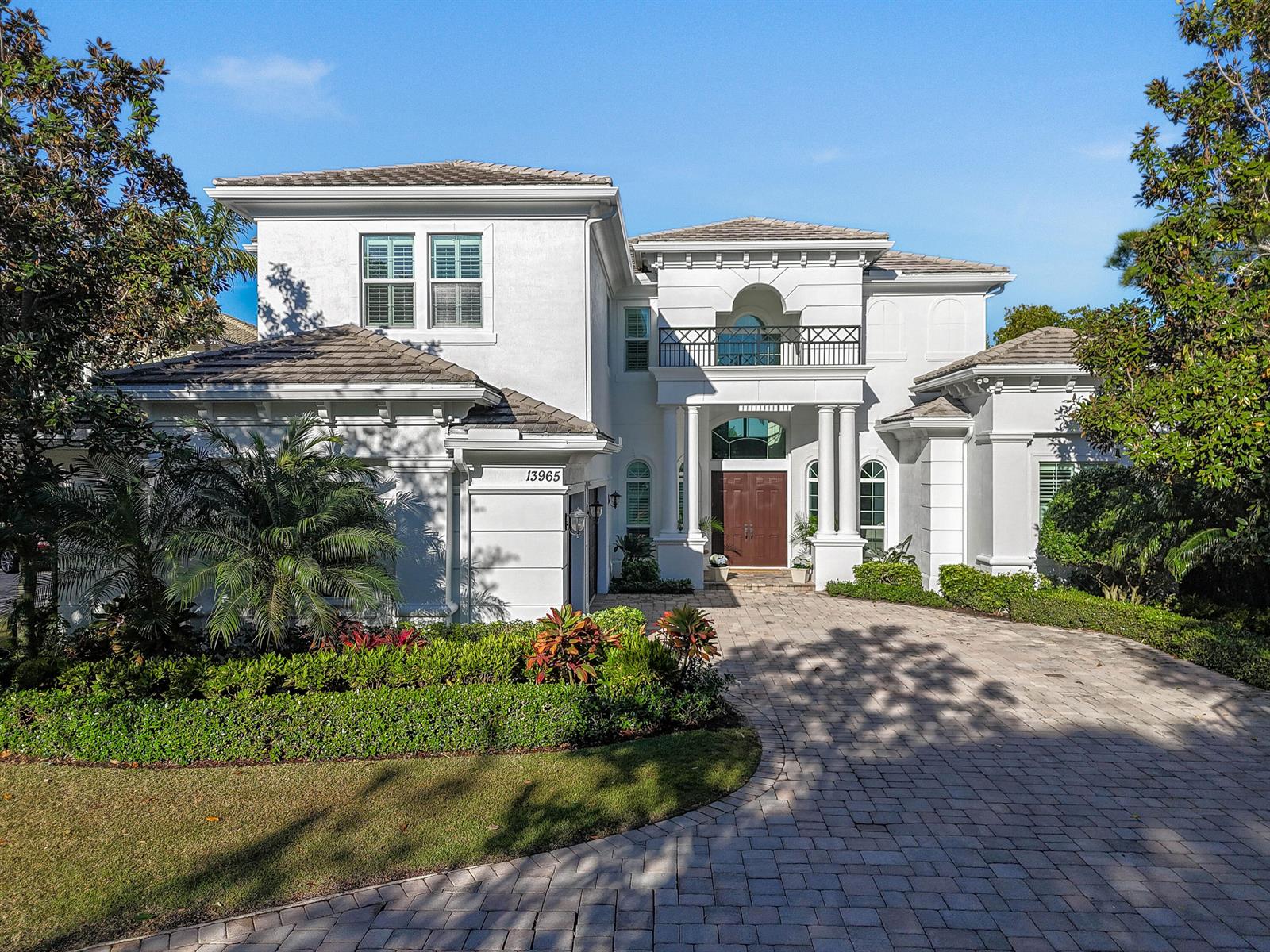 A two-story white stucco house features a paved driveway, arched entryway, and a second-floor balcony — 13965 Willow Cay Drive, Juno Beach FL 33408, JUNO BEACH, FL