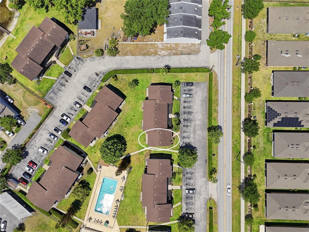 An aerial view shows a rectangular swimming pool surrounded by lounge chairs and apartment buildings — 900 AVENUE Z SE UNIT A1, WINTER HAVEN, FL
