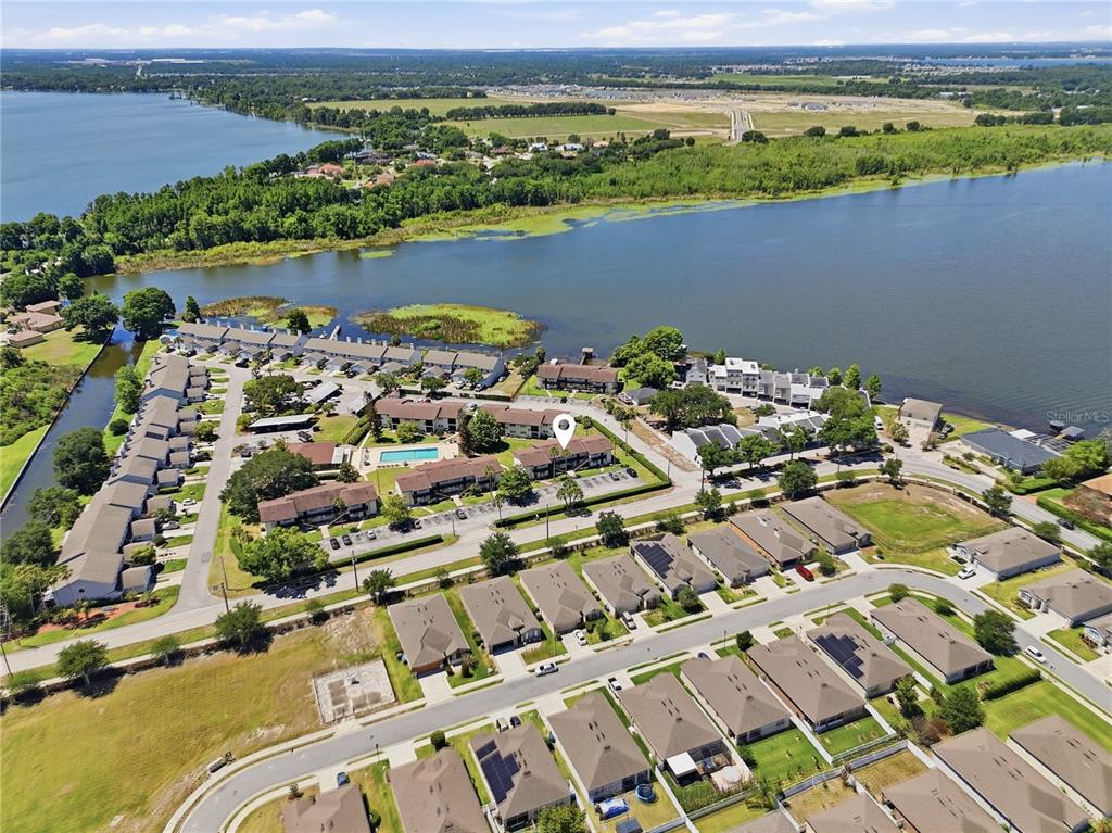 An aerial view shows a multi-story apartment building with a parking lot and lake — 900 AVENUE Z SE UNIT A1, WINTER HAVEN, FL