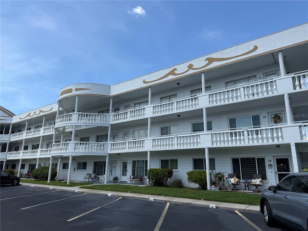 A three-story white apartment building with curved balconies and a parking lot in front — 2428 COLUMBIA DRIVE UNIT 68, CLEARWATER, FL
