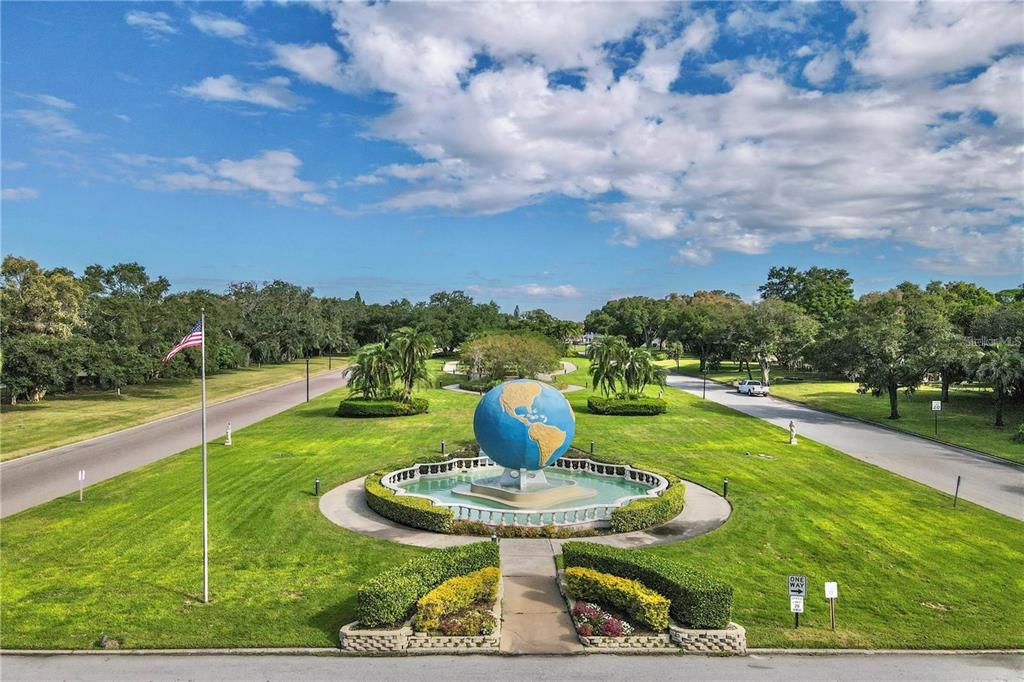 A large globe sculpture sits in a fountain surrounded by a lawn and paved roads — 2428 COLUMBIA DRIVE UNIT 68, CLEARWATER, FL