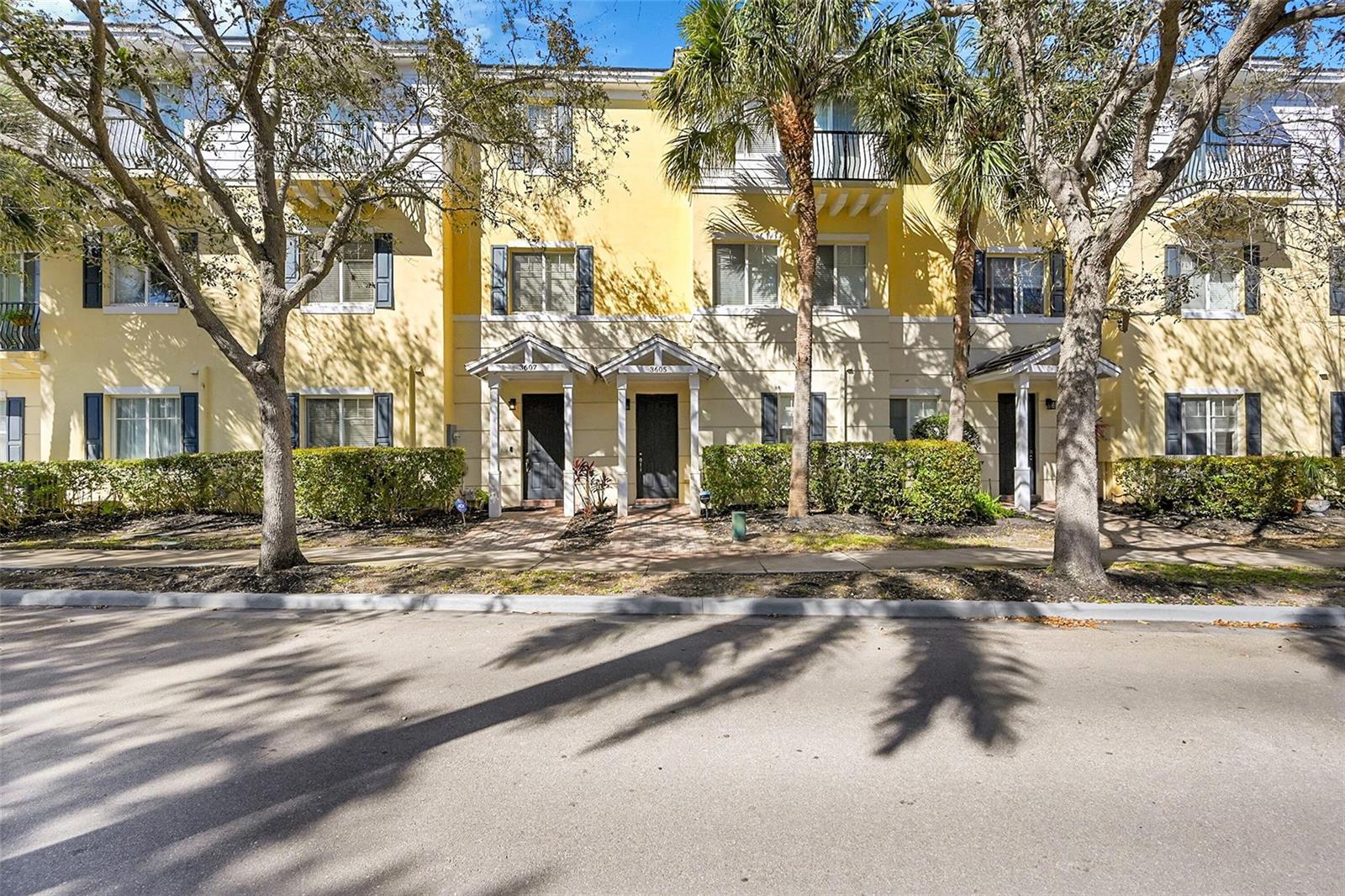 A row of yellow three-story townhouses features dark doors, balconies, and palm trees in front — 3605 NW 5th Terrace, Boca Raton FL 33431, BOCA RATON, FL