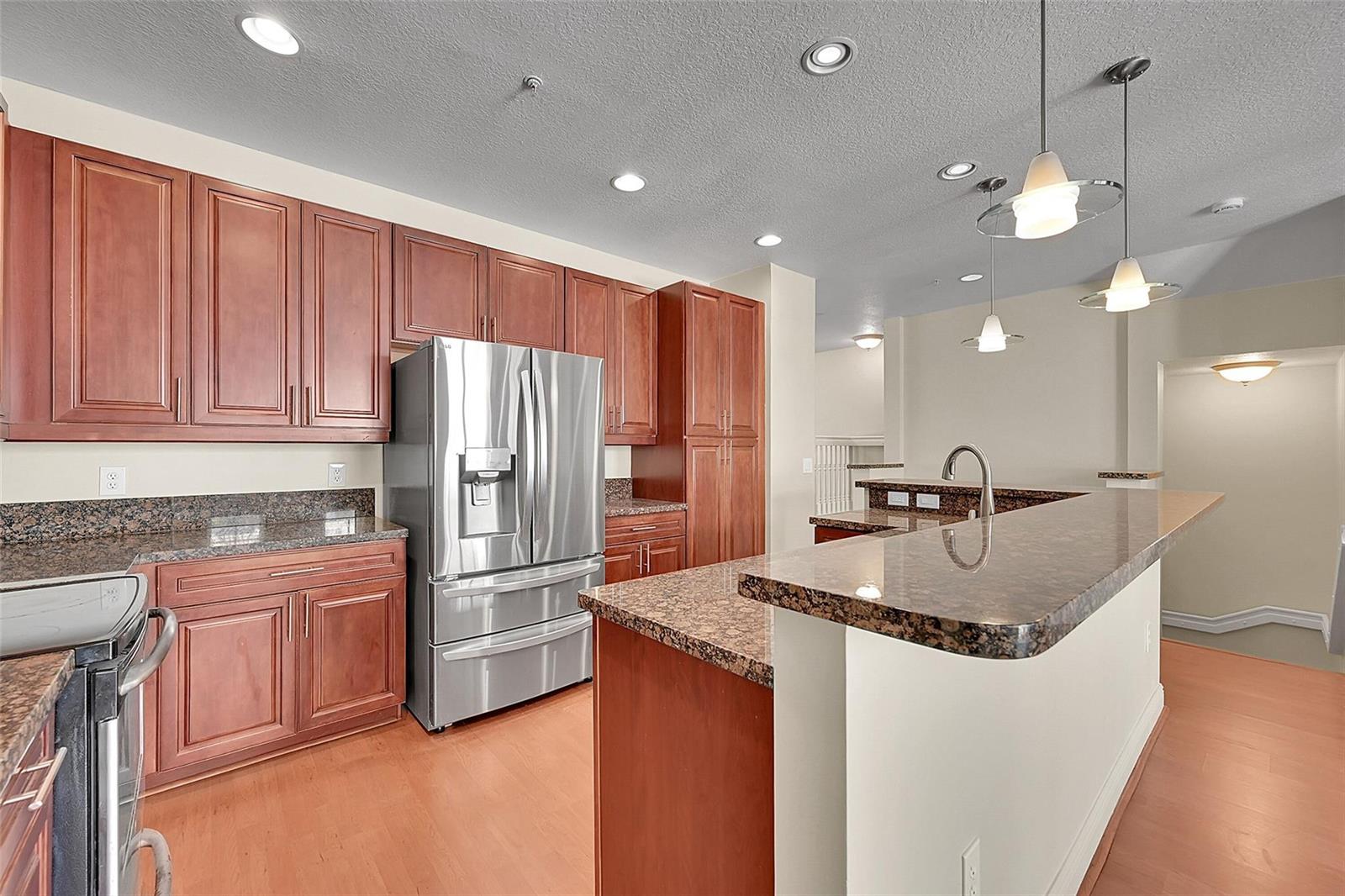 A kitchen features cherry wood cabinets, granite countertops, stainless steel appliances, and a breakfast bar — 3605 NW 5th Terrace, Boca Raton FL 33431, BOCA RATON, FL