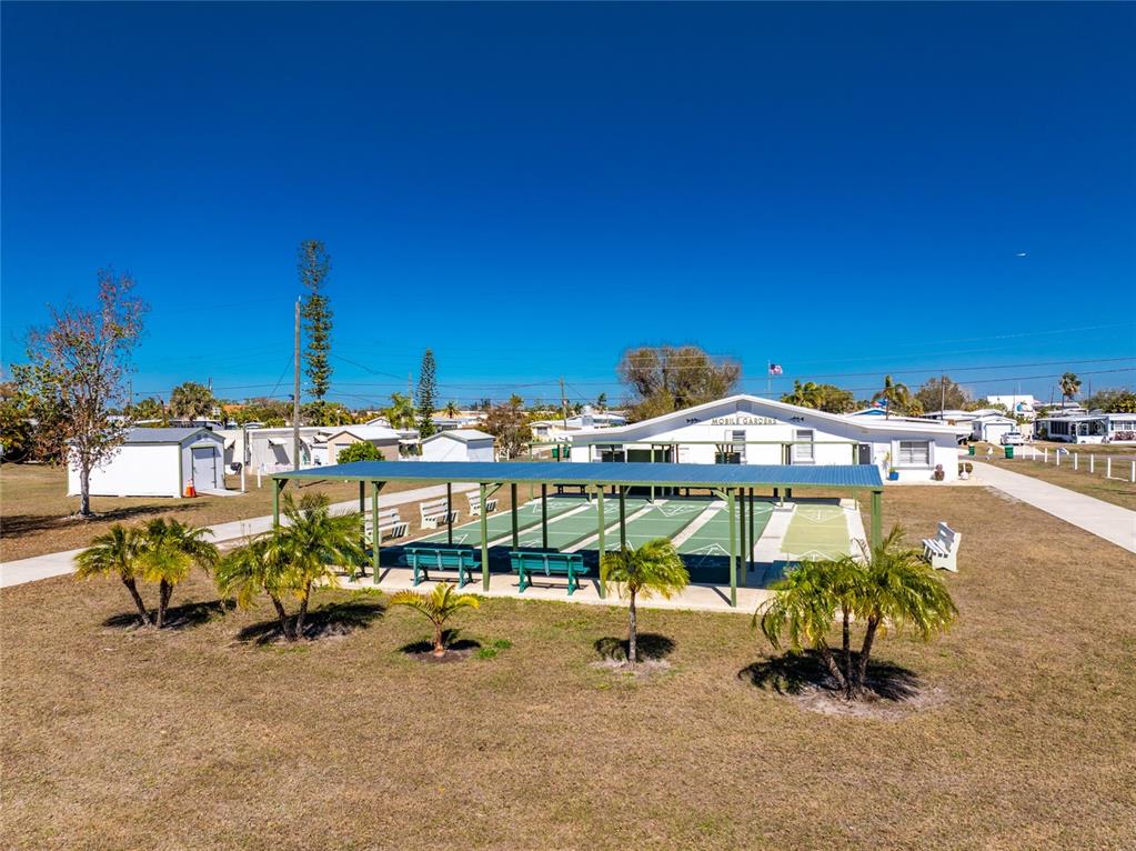 An outdoor shuffleboard court with a covered pavilion sits in front of a community building — 258 VIA DE LUNA, ENGLEWOOD, FL