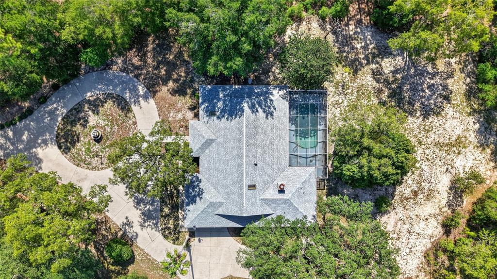 An aerial view shows a house with a screened-in pool surrounded by trees and landscaping — 9000 SW 203RD COURT, DUNNELLON, FL