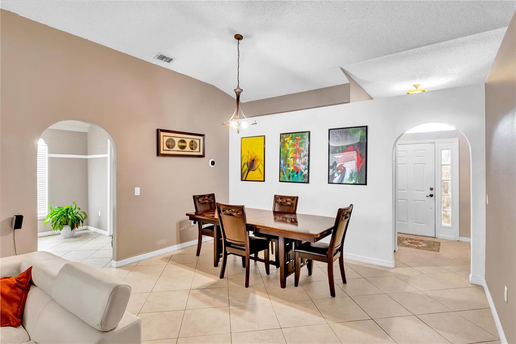 A dining area with a wooden table, four chairs, and three framed pictures on the wall — 206 GREAT YARMOUTH COURT, KISSIMMEE, FL