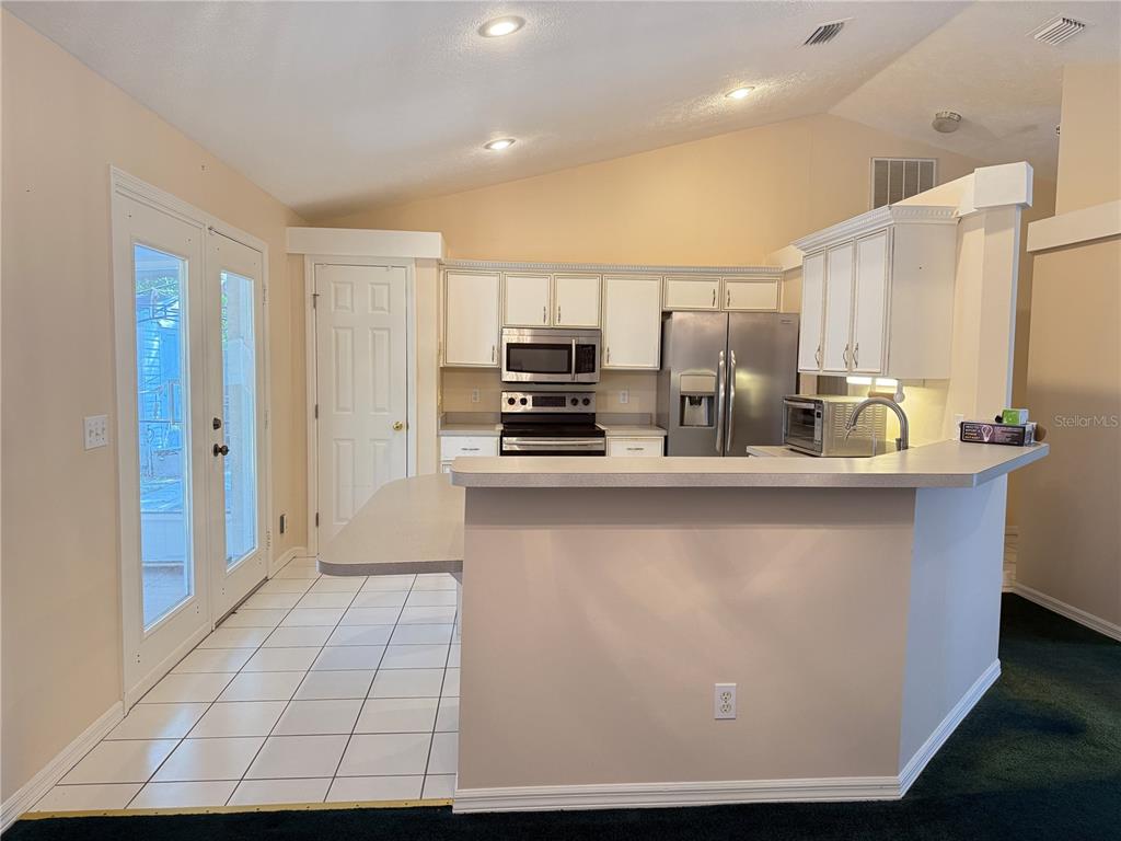 A kitchen with white cabinets, stainless steel appliances, and a breakfast bar overlooking a tiled floor — 4262 NE 35TH AVENUE ROAD, OCALA, FL