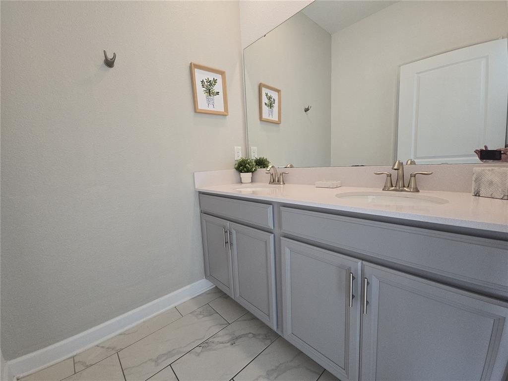 A bathroom features a double vanity with gray cabinets, white countertops, and a large mirror — 1036 LEADER STREET, DAVENPORT, FL