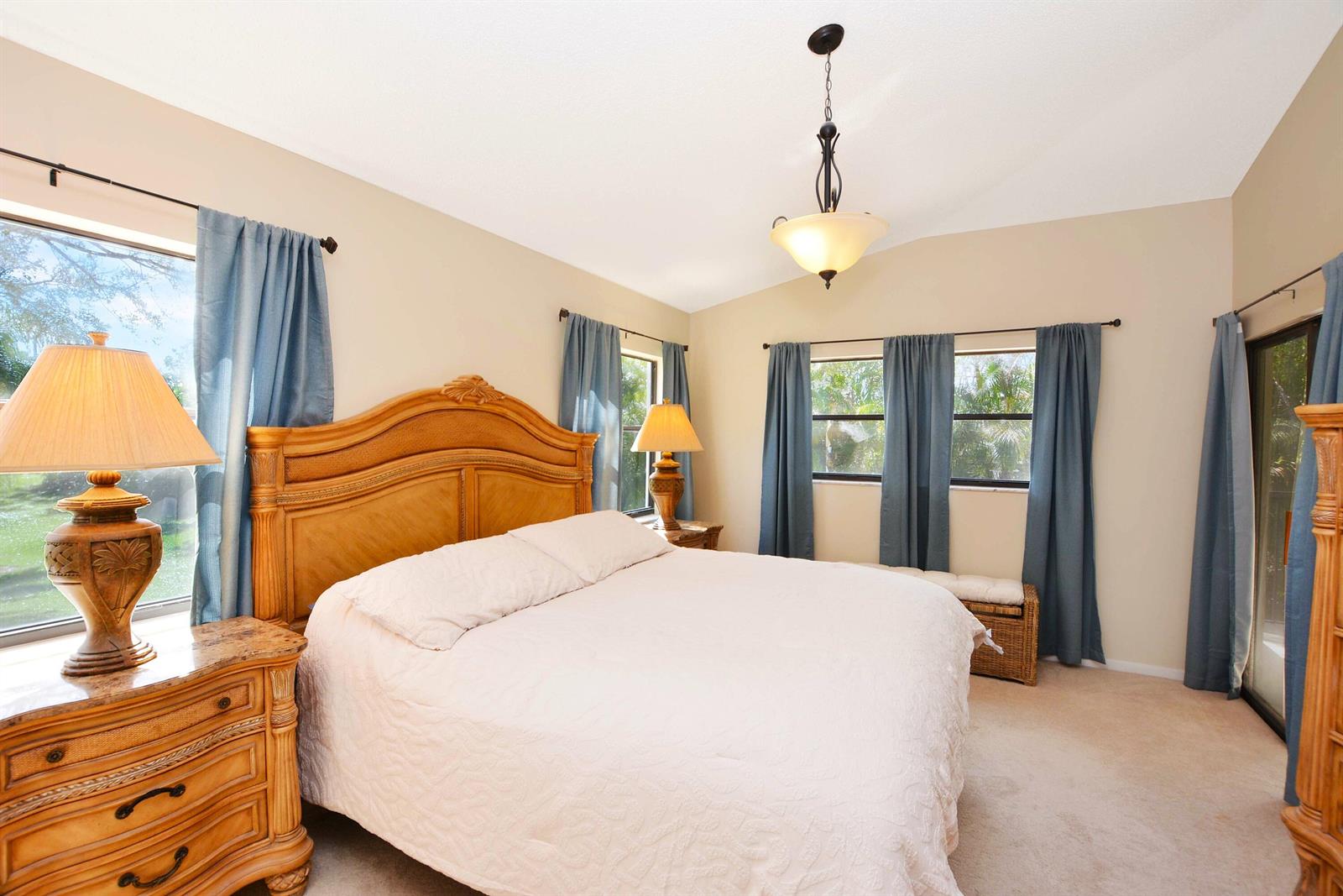 A bedroom features a wooden bed frame, two nightstands with lamps, and blue curtains — 2406 Aspen Way # 2406, Boynton Beach FL 33436, BOYNTON BEACH, FL