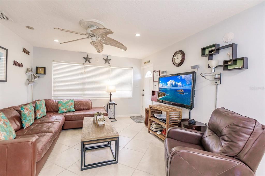 A living room features a brown leather sectional, a matching armchair, and a television console — 6020 MIDNIGHT PASS ROAD UNIT 59, SARASOTA, FL