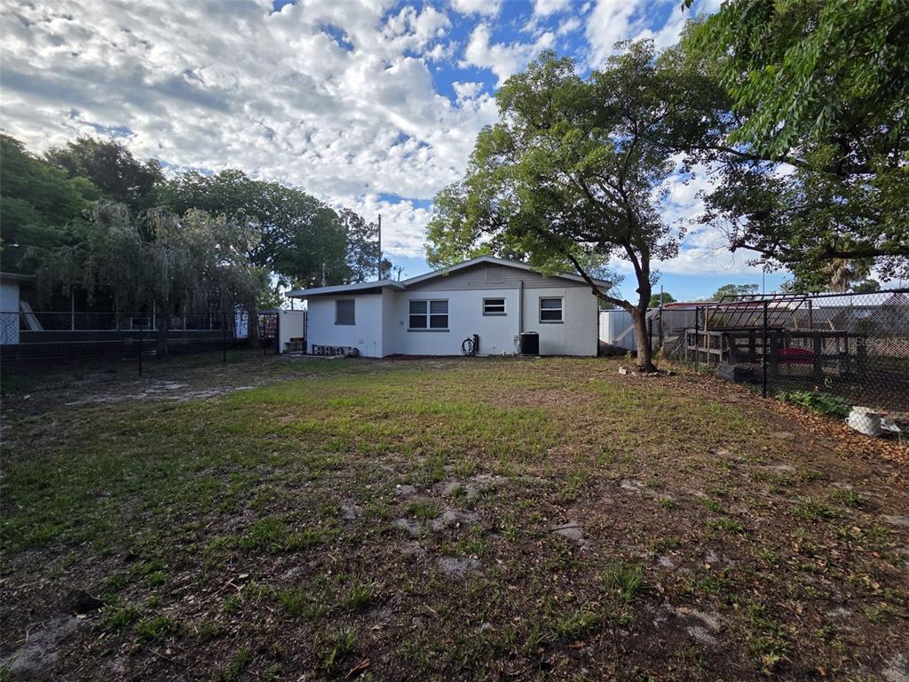 A single-story house with a white exterior sits behind a large, grassy backyard — 7216 JAMES STREET, PORT RICHEY, FL