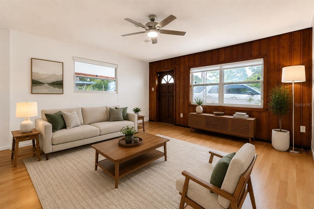 A living room features a beige sofa, wood coffee table, and wood-paneled accent wall — 7216 JAMES STREET, PORT RICHEY, FL