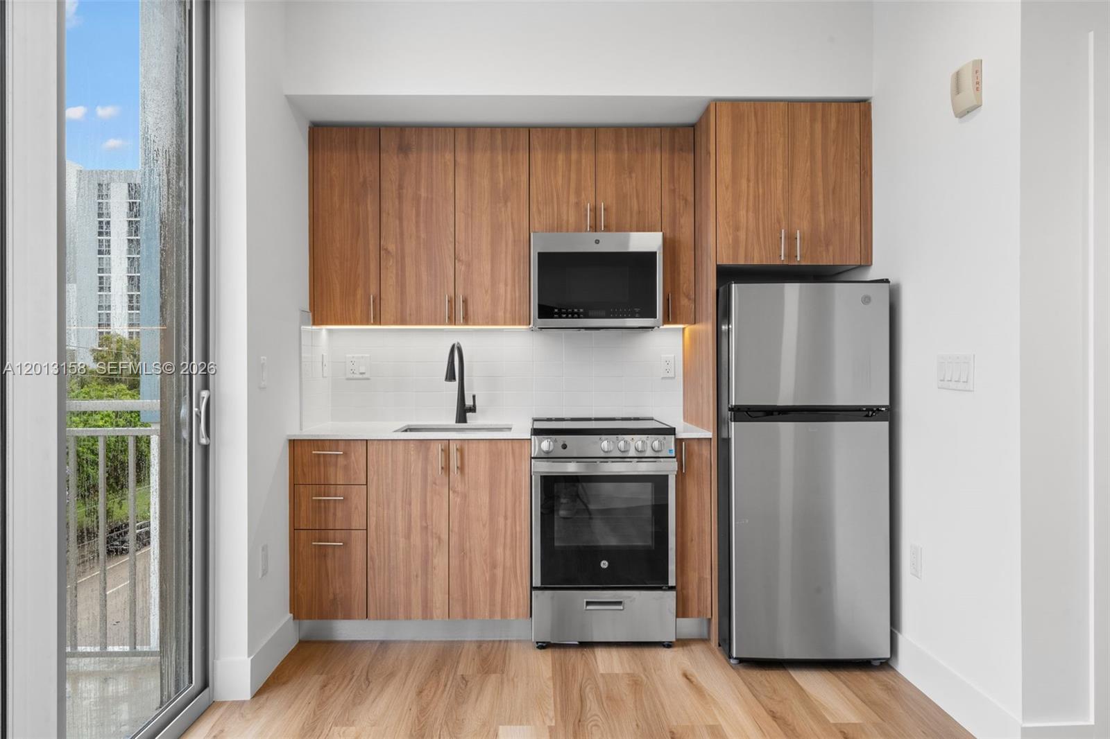 A modern kitchen features wood-grain cabinets, stainless steel appliances, and a white tiled backsplash — 650 SW 1st St # 206, Miami FL 33130, MIAMI, FL