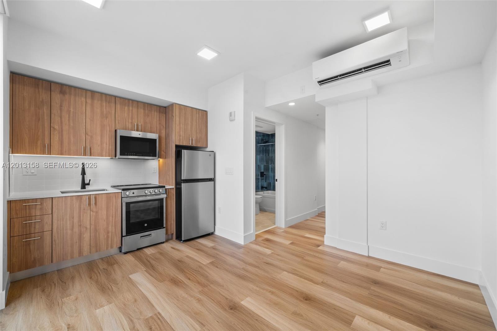 A modern kitchen features wood-toned cabinets, stainless steel appliances, and light wood flooring — 650 SW 1st St # 206, Miami FL 33130, MIAMI, FL