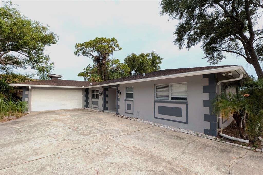 A single-story gray house with a white garage door and dark corner trim — 3273 HARBOR LAKE DRIVE, LARGO, FL