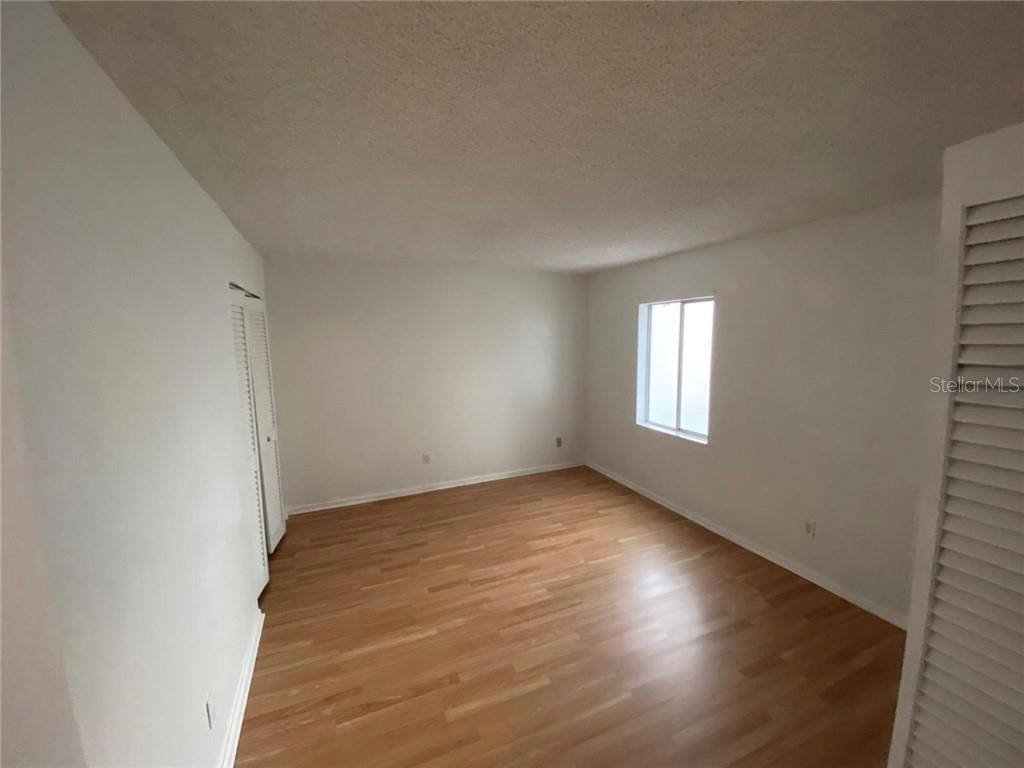 An empty bedroom features light wood-look flooring, white walls, and a single window — 7508 PRESLEY PLACE UNIT 100, TAMPA, FL