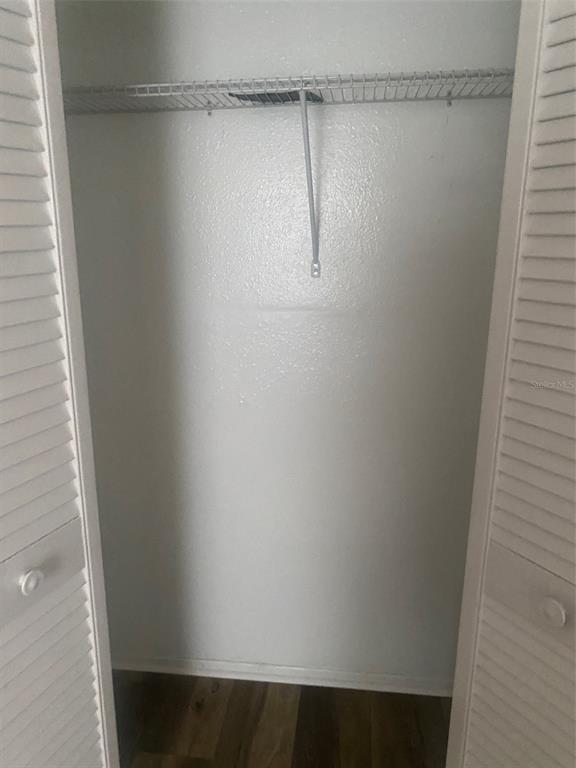 A closet with white louvered doors, a wire shelf, and wood-look flooring — 7508 PRESLEY PLACE UNIT 100, TAMPA, FL