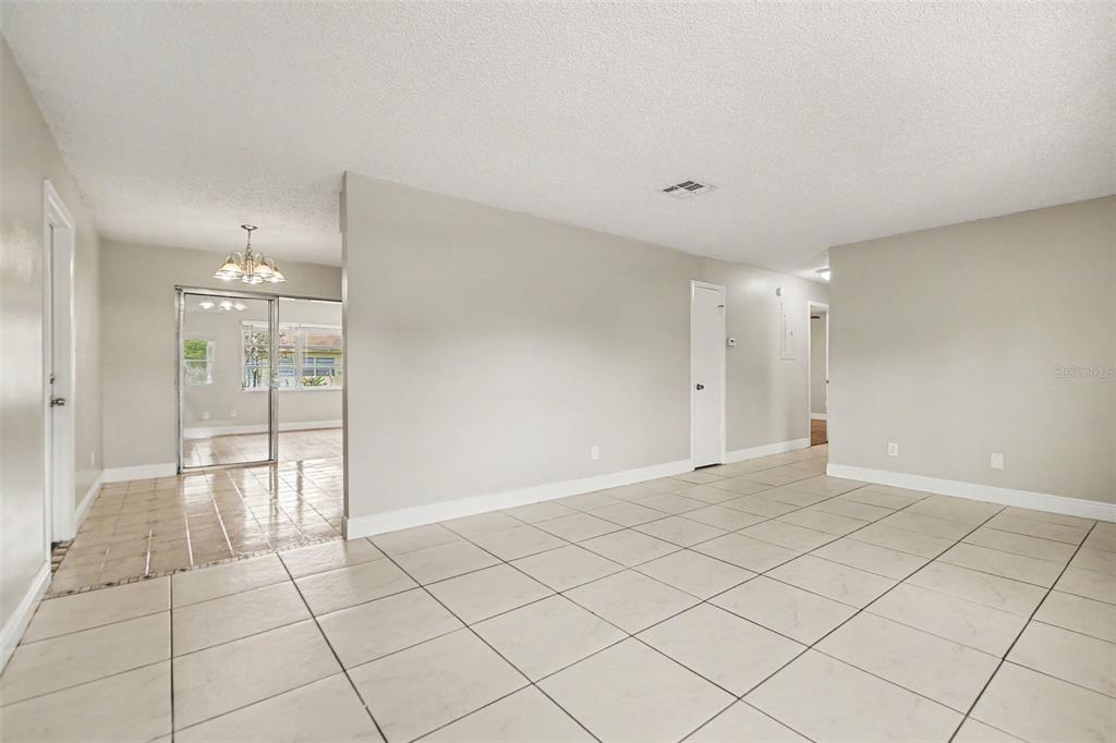 A spacious room with light-colored tile flooring, white walls, and a view into another area — 140 GUAYMAS DRIVE, KISSIMMEE, FL