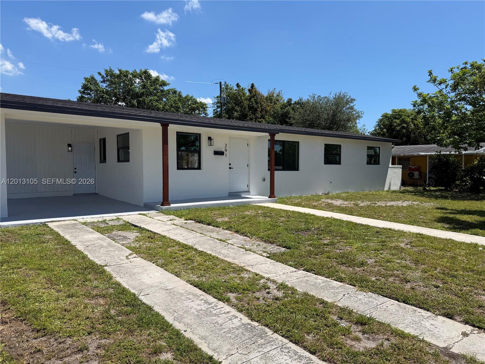 A white single-story house features a carport, a front porch, and a concrete driveway — 291 NW 184th Ter, Miami Gardens FL 33169, MIAMI GARDENS, FL