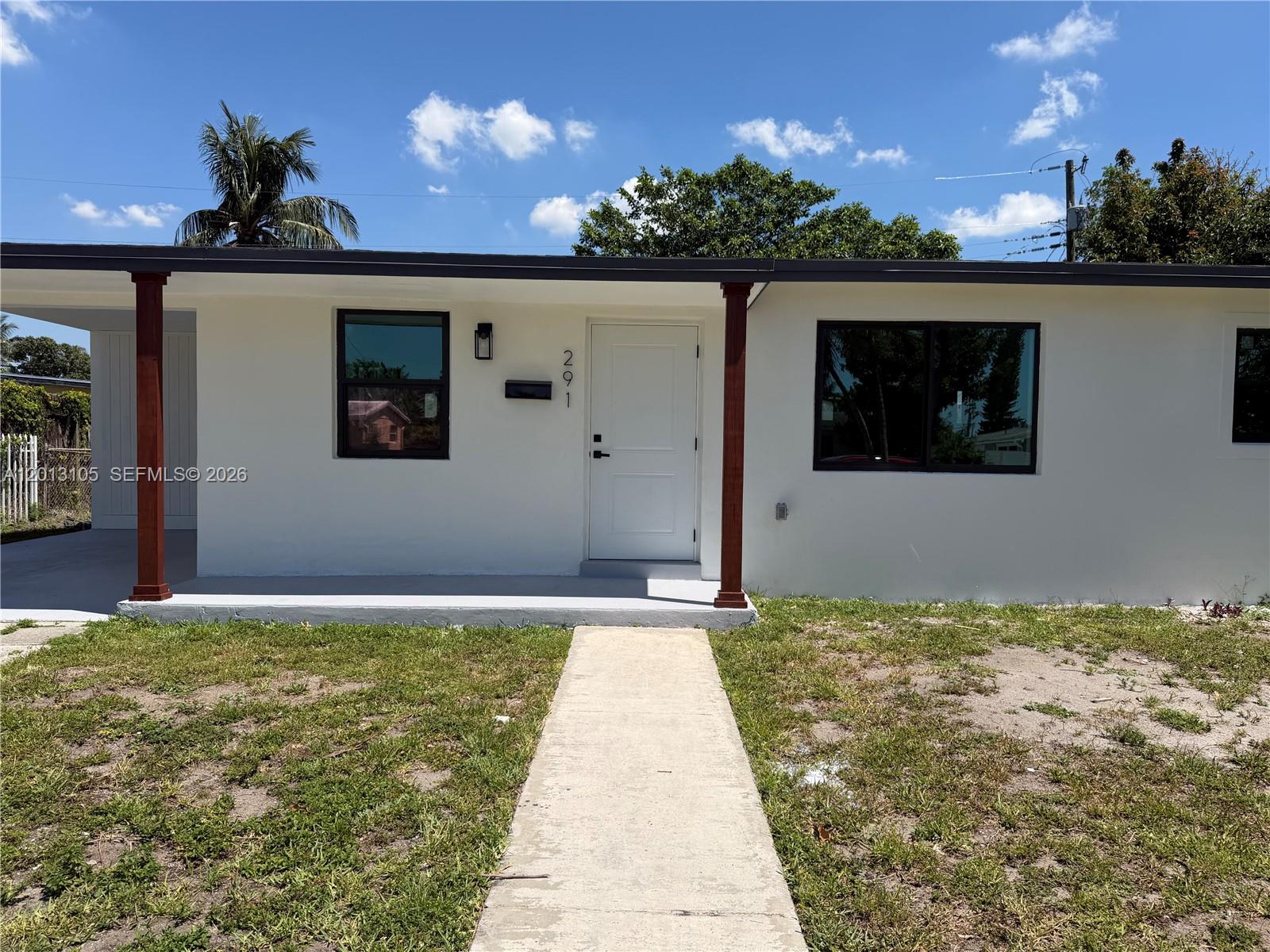 The exterior of a white, single-story house features a front porch with two wooden columns — 291 NW 184th Ter, Miami Gardens FL 33169, MIAMI GARDENS, FL