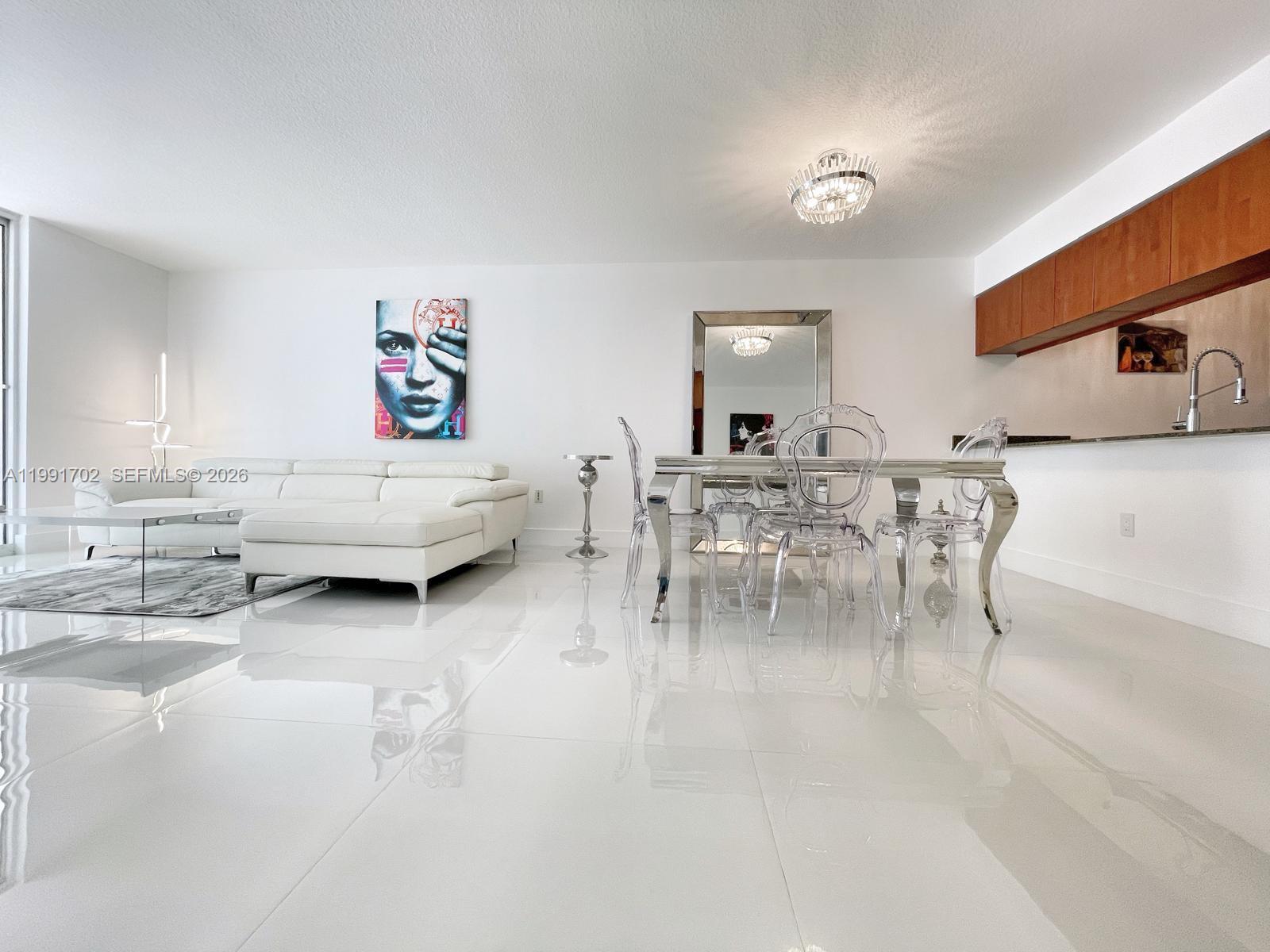 A modern, open-concept living and dining area features white tile floors and contemporary furniture — 1200 SE Brickell Bay Dr # 1707, Miami FL 33131, MIAMI, FL