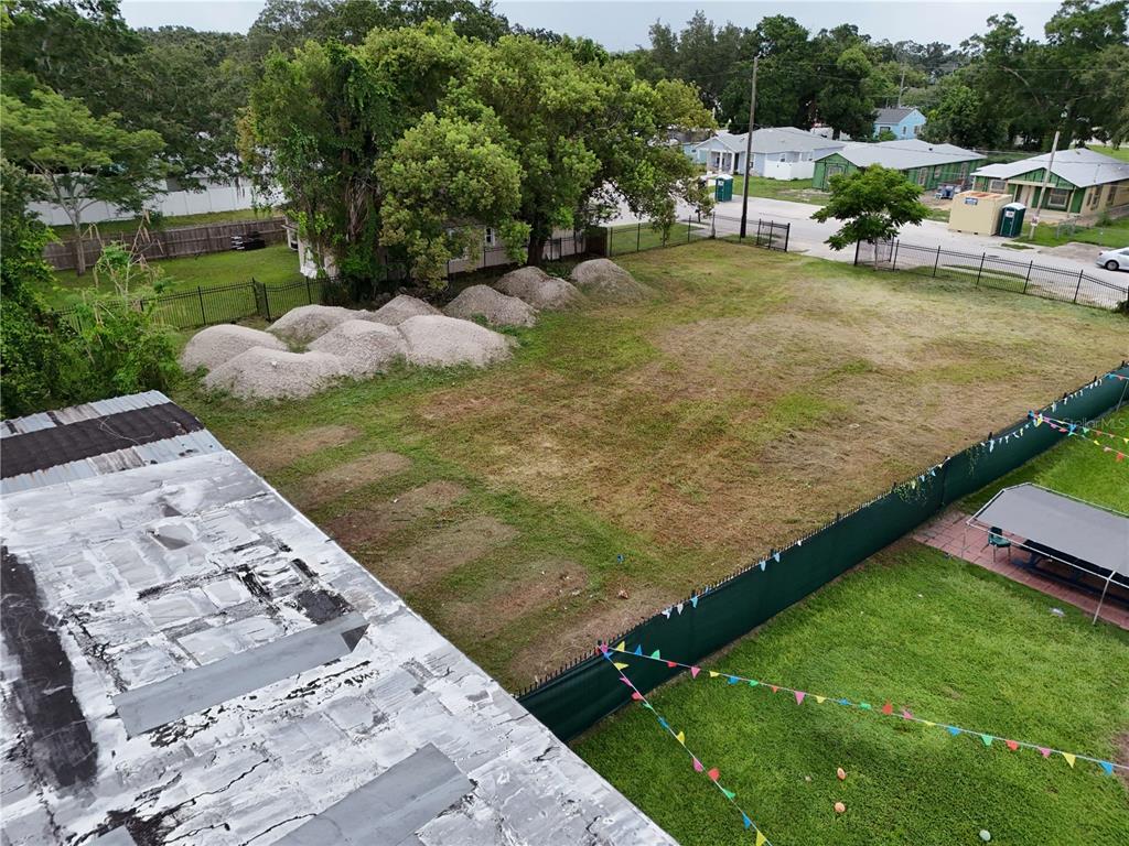 An elevated view shows a vacant, grassy lot with piles of gravel and perimeter fencing — 1221 25TH STREET, ORLANDO, FL