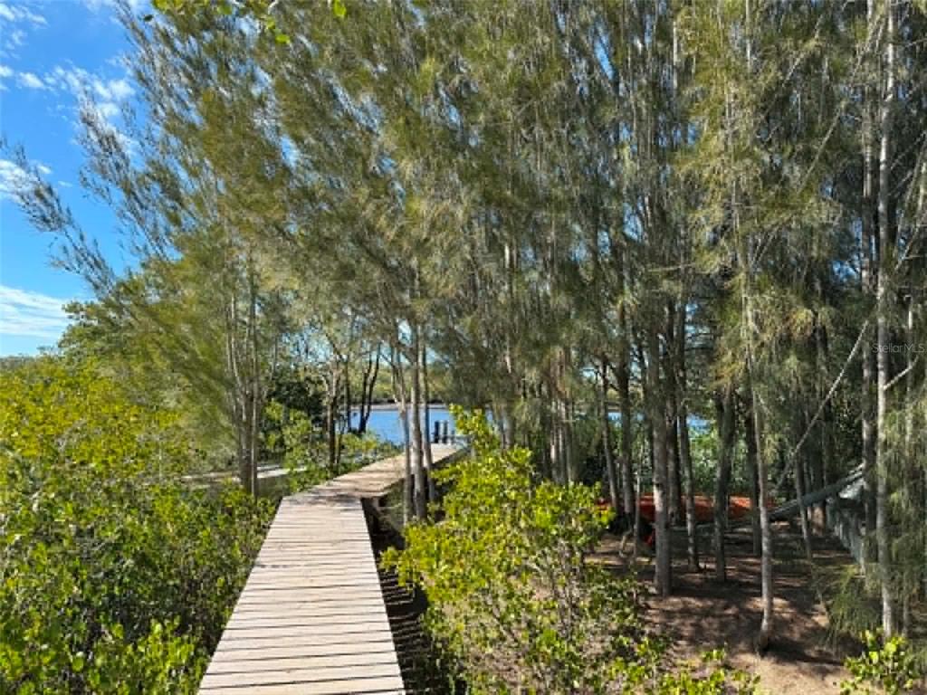 A wooden boardwalk leads through trees toward a body of water — 1348 S ESTUARY DRIVE, CRYSTAL RIVER, FL