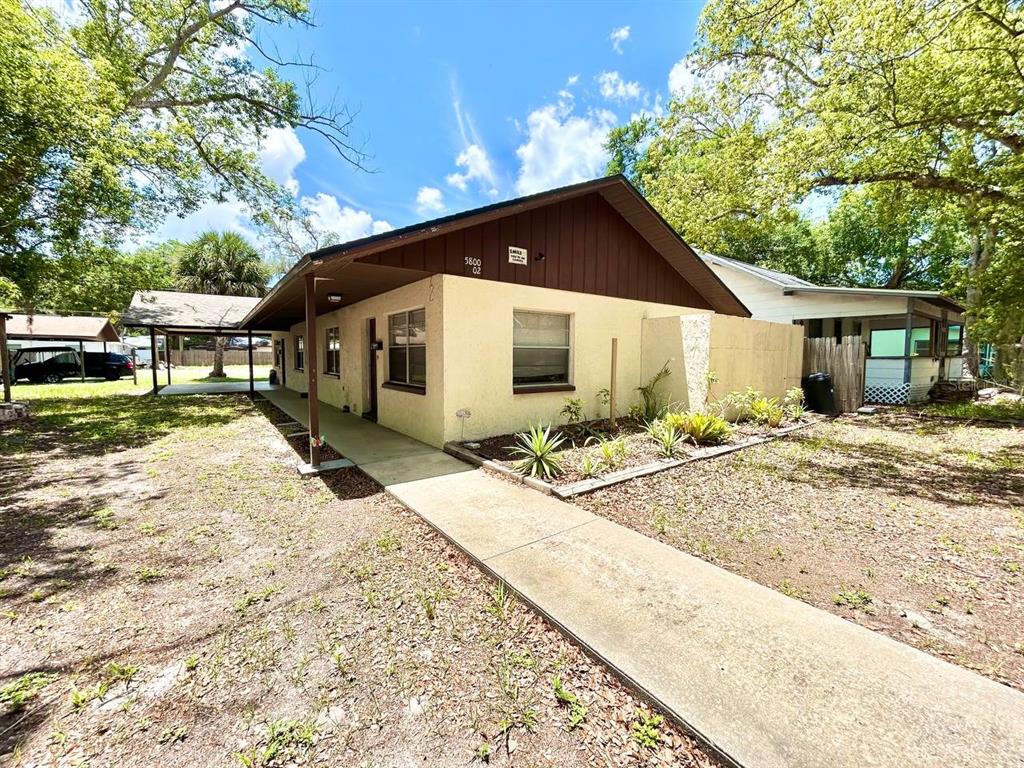 A single-story house with a beige stucco exterior, brown trim, and a concrete walkway — 5800 MONTANA AVENUE, NEW PORT RICHEY, FL
