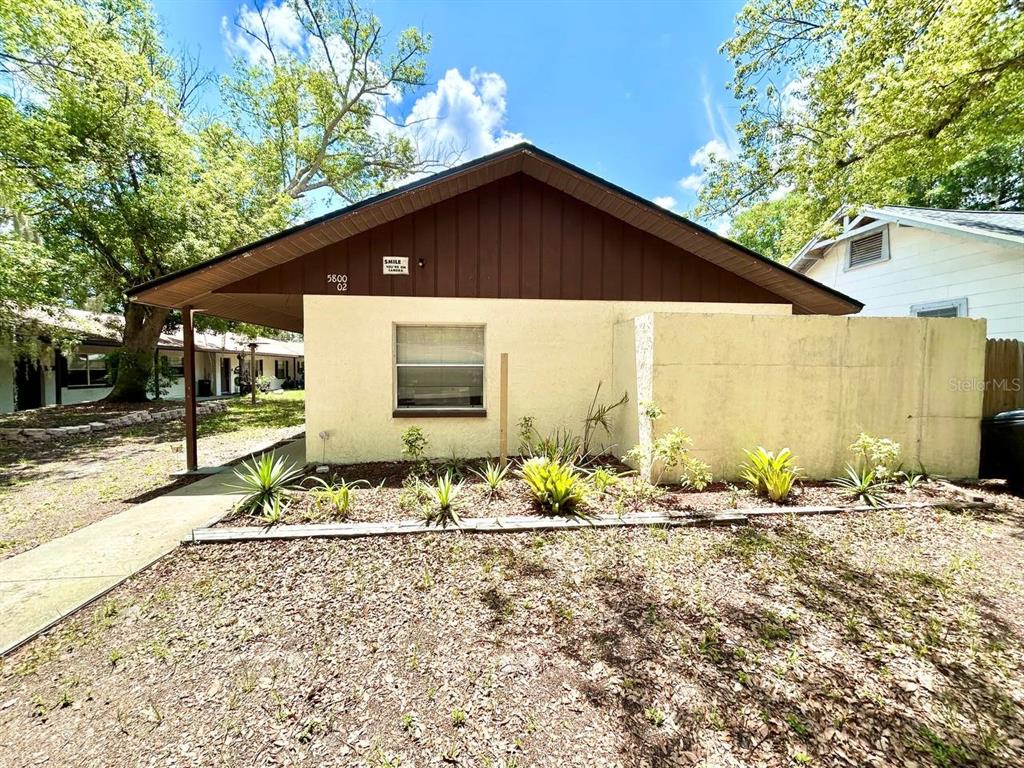 A single-story house with a beige stucco exterior, a brown gable roof, and a carport — 5800 MONTANA AVENUE, NEW PORT RICHEY, FL