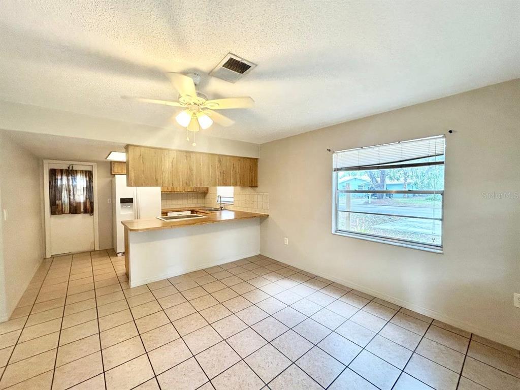 A kitchen and dining area with tile flooring, wood cabinets, and a ceiling fan — 5800 MONTANA AVENUE, NEW PORT RICHEY, FL