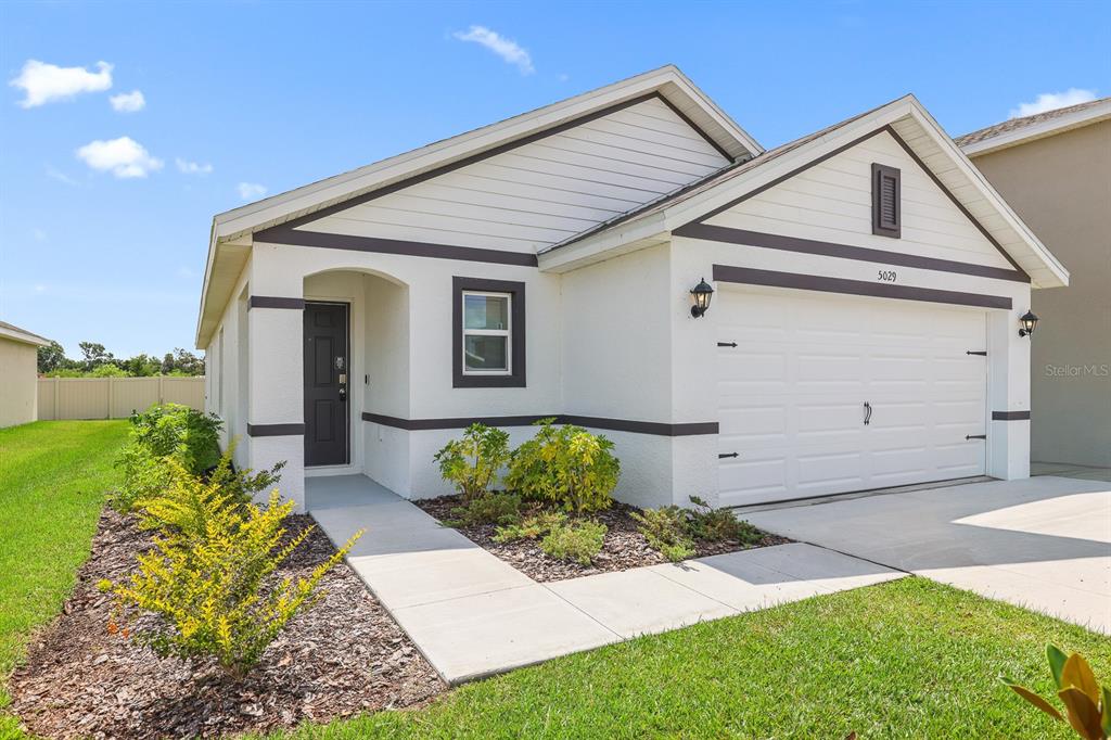 A single-story house with white stucco walls, dark trim, and a two-car garage — 5029 ROCKY COAST PLACE, PALMETTO, FL