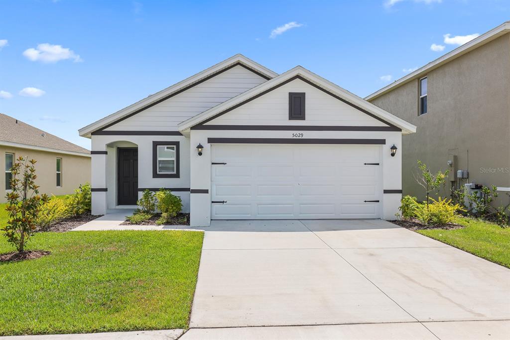 A single-story house with a white garage, dark trim, and a concrete driveway — 5029 ROCKY COAST PLACE, PALMETTO, FL